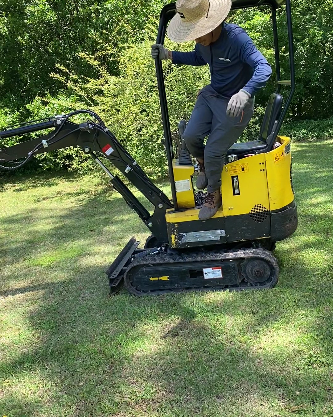 An All About Trees crew member working from a compact tracked excavator on a customer's lawn